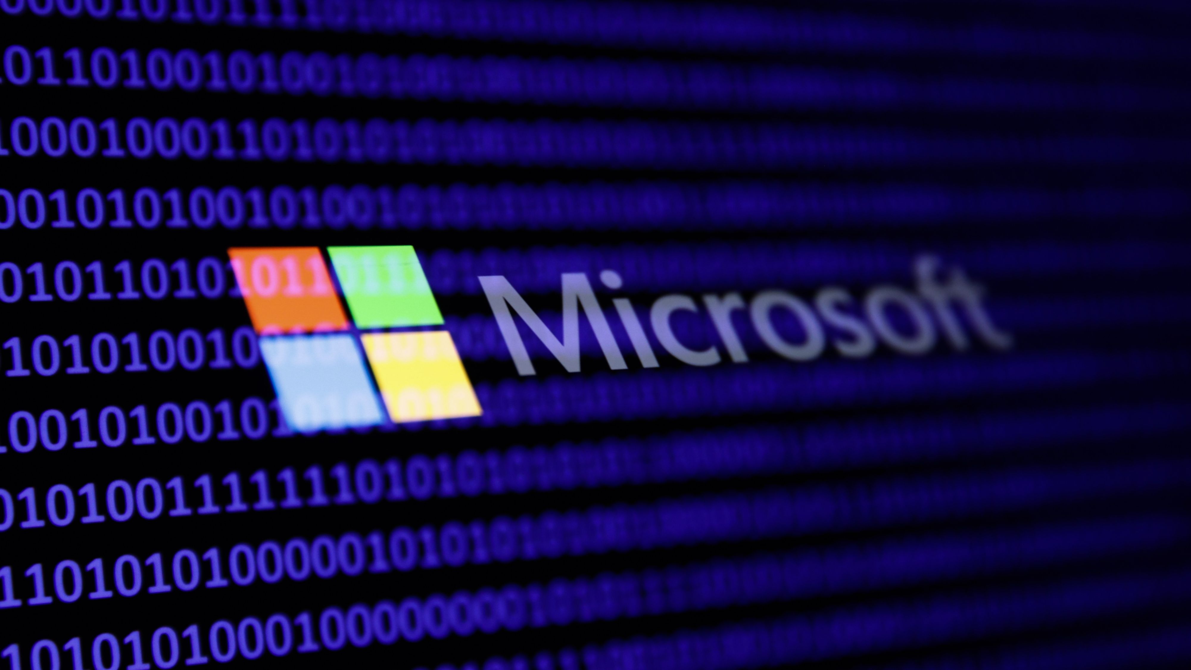 A binary code and Microsoft logo are seen in this multpiple exposure illustration photo.
