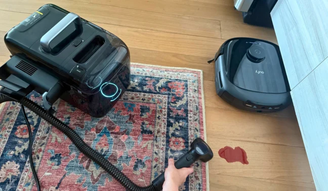 Person cleaning rug with Eufy E28 carpet cleaner while robot vacuum mops hardwood floor