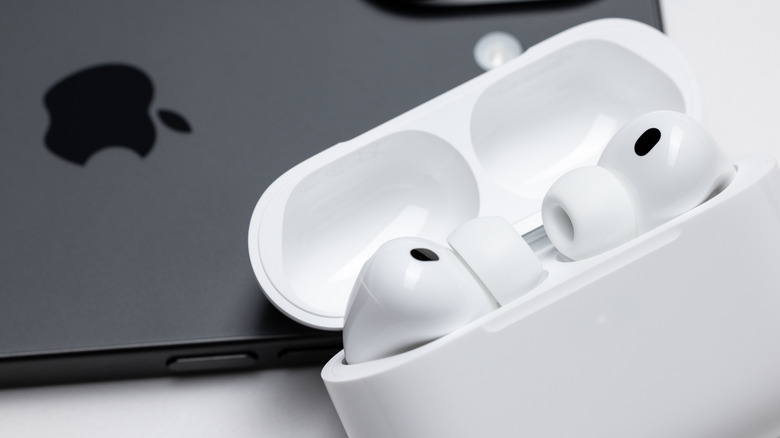 Airpods Pro sitting in their open case next to an iPhone