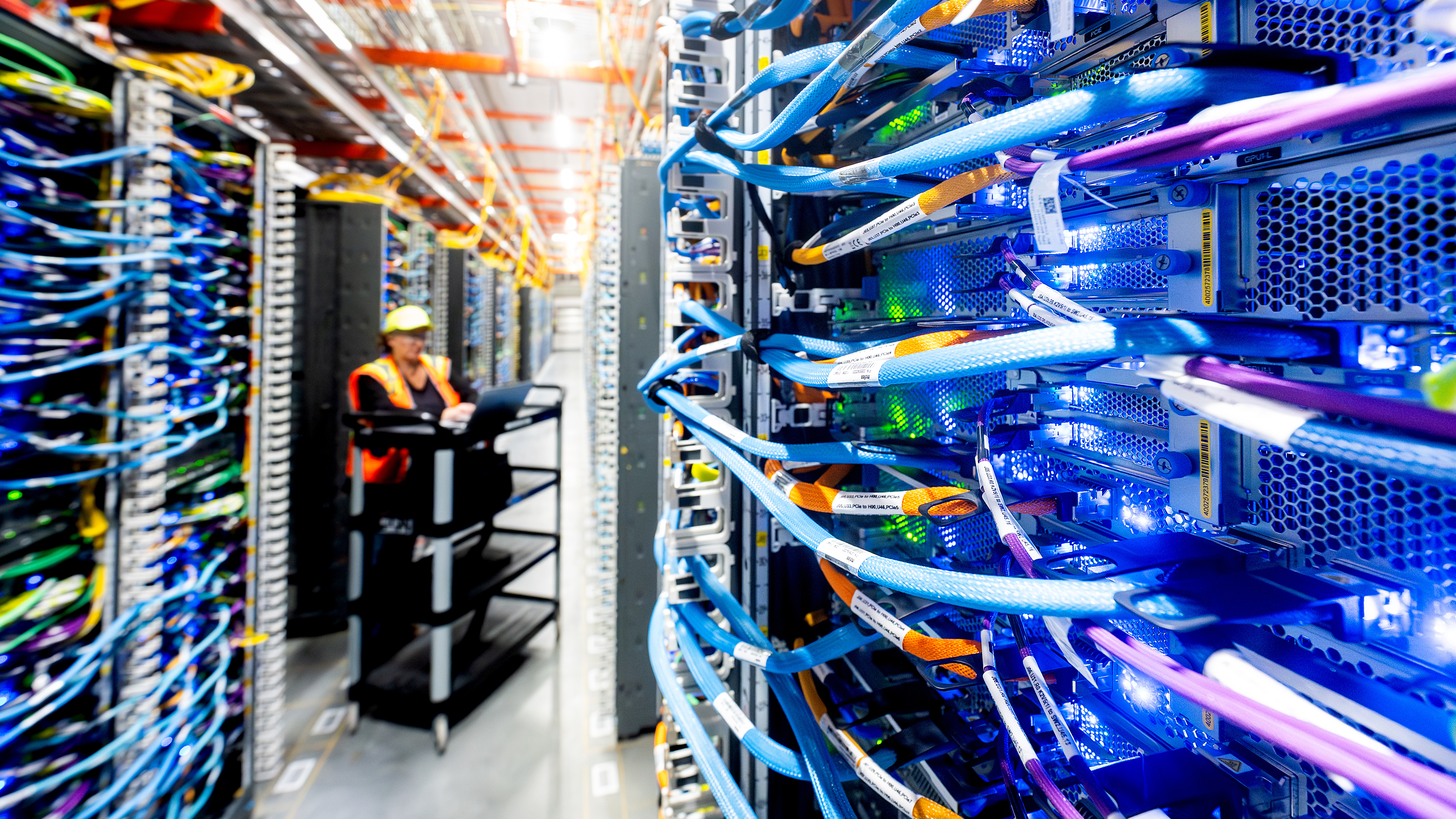 Amazon data center technician maintaining racks of networking equipment