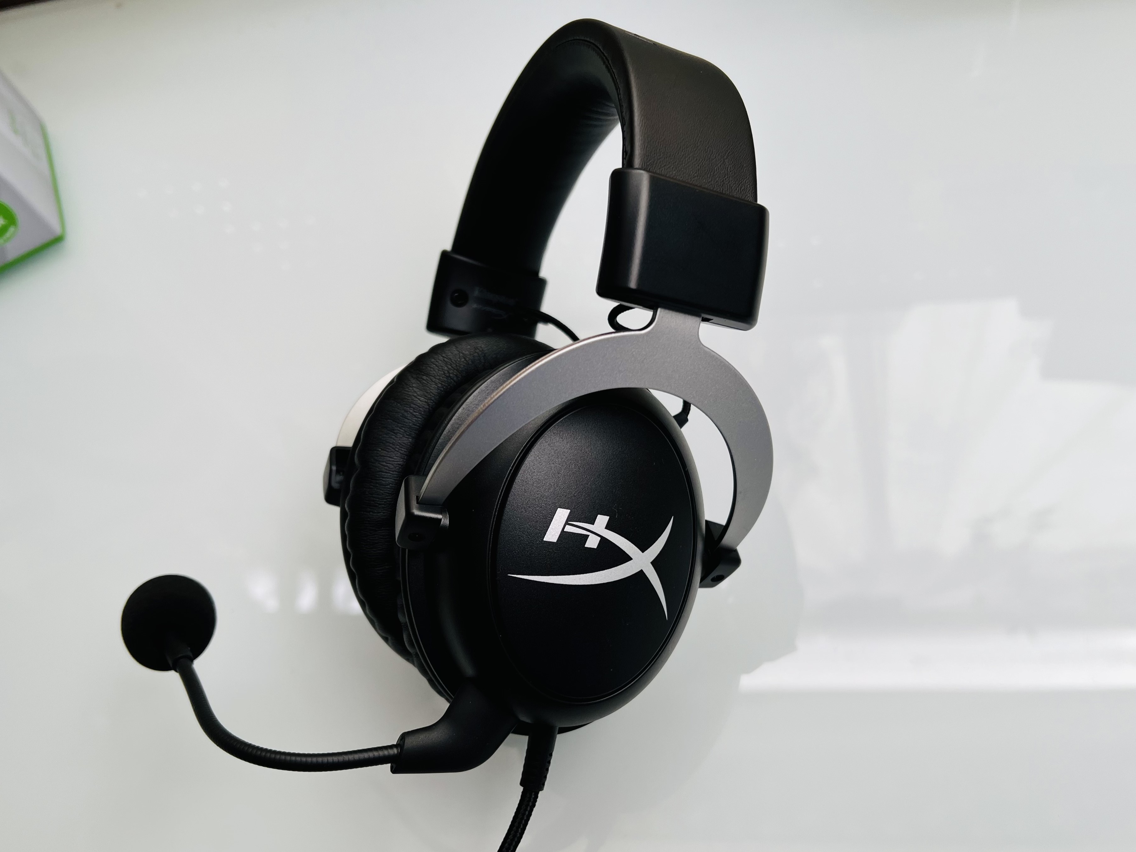 Black and silver gaming headset with microphone on a white surface, featuring cushioned ear pads and an adjustable headband, conveying a modern tech vibe.