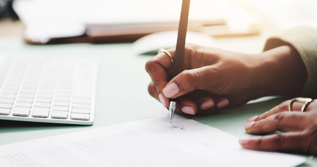 Contract, hands and writing with business person at desk in office to sign draft or proposal. Agreement, documents and paperwork with signature of employee closeup at work for management approval