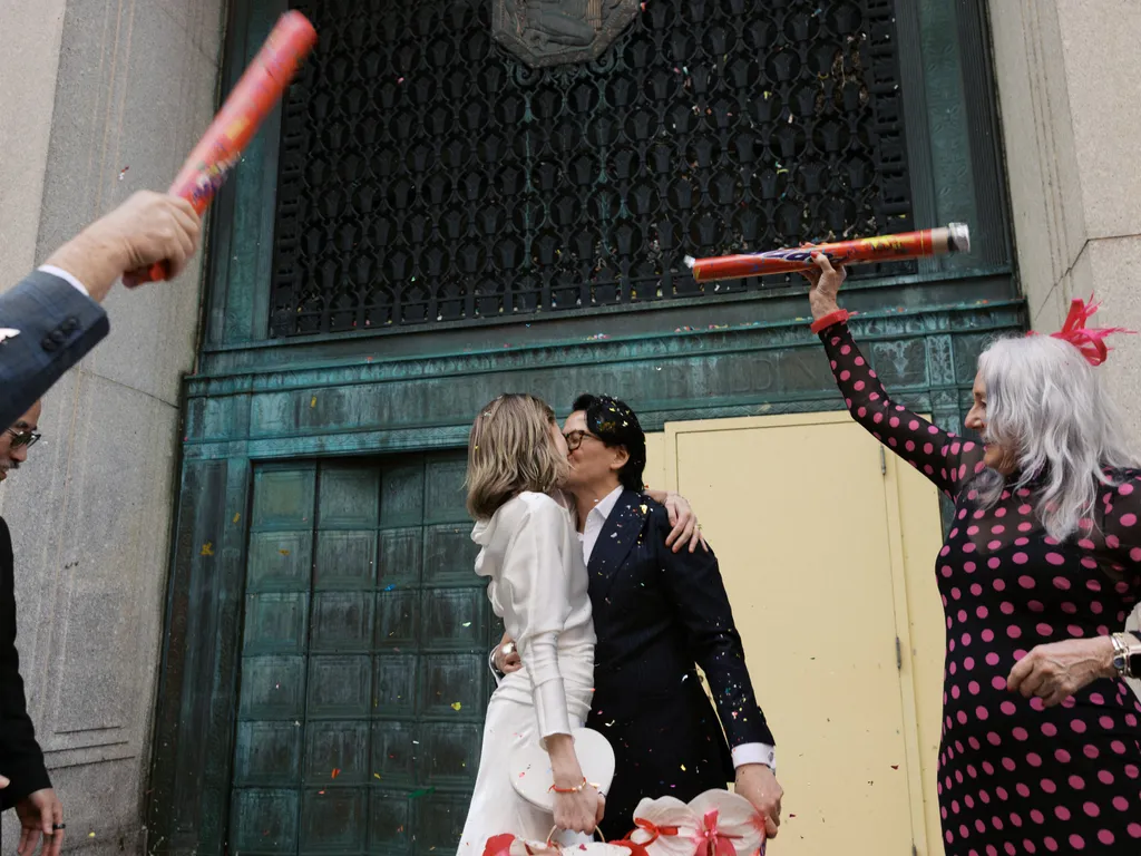 Image may contain Blazer Clothing Coat Jacket Adult Person Dress Kissing Romantic Wedding Formal Wear and People