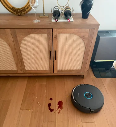 Narwal Flow 2 robot vacuum cleaning wine spill on hardwood floor