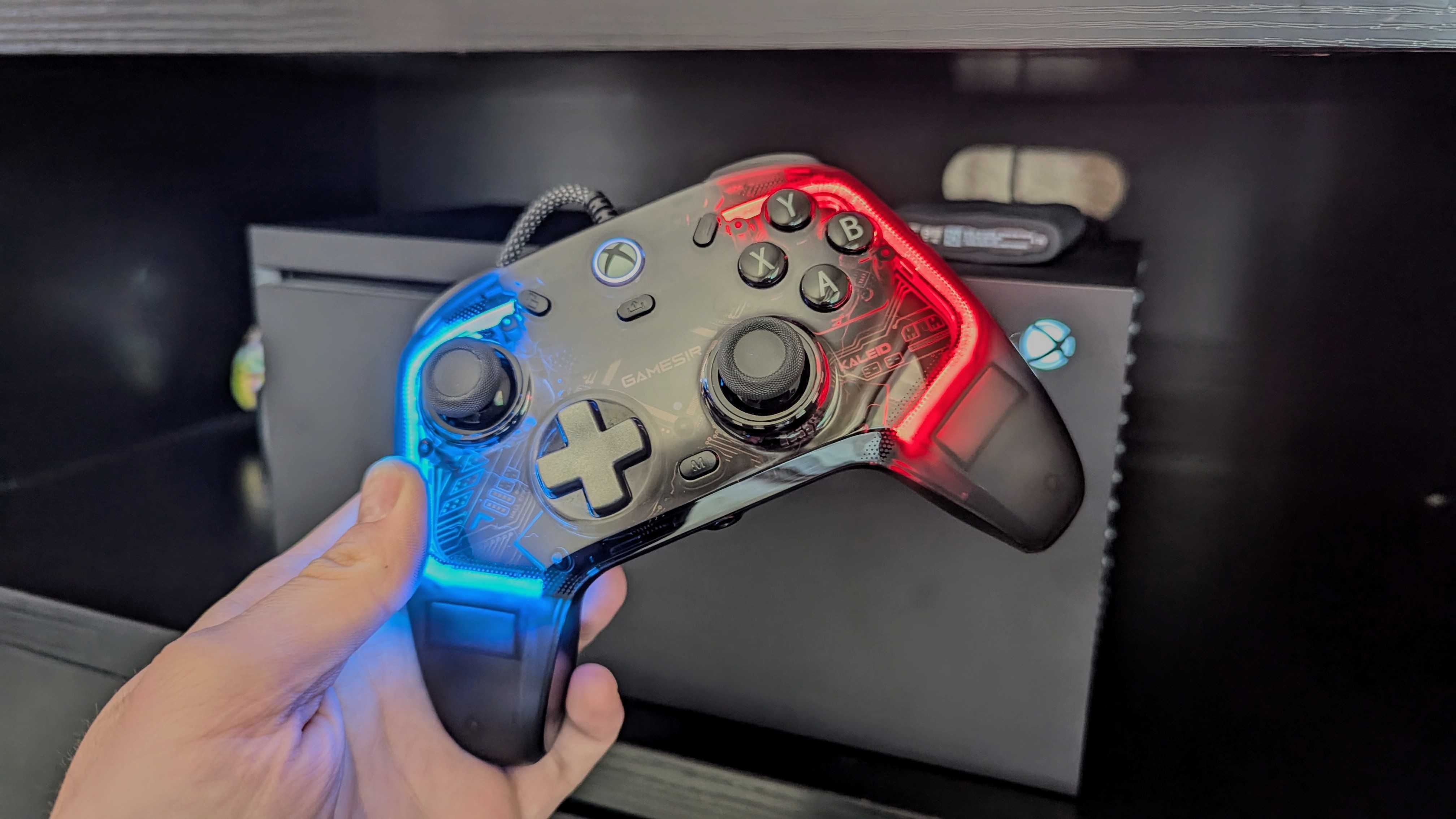 A hand holds a GameSir Kaleid Controller for Xbox with vibrant blue and red lights, set in front of an Xbox console. The scene conveys a modern, tech-savvy vibe.