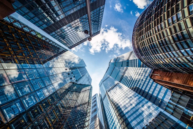 Dramatic Low Angle View of Modern Glass Skyscrapers Forming Urban Canyon Against Blue Sky