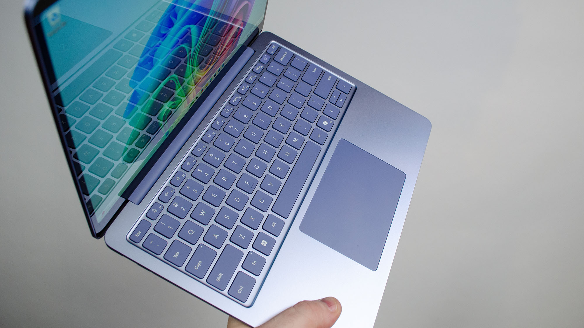 A masculine hand holding the Microsoft Surface Laptop 13-inch at an angle