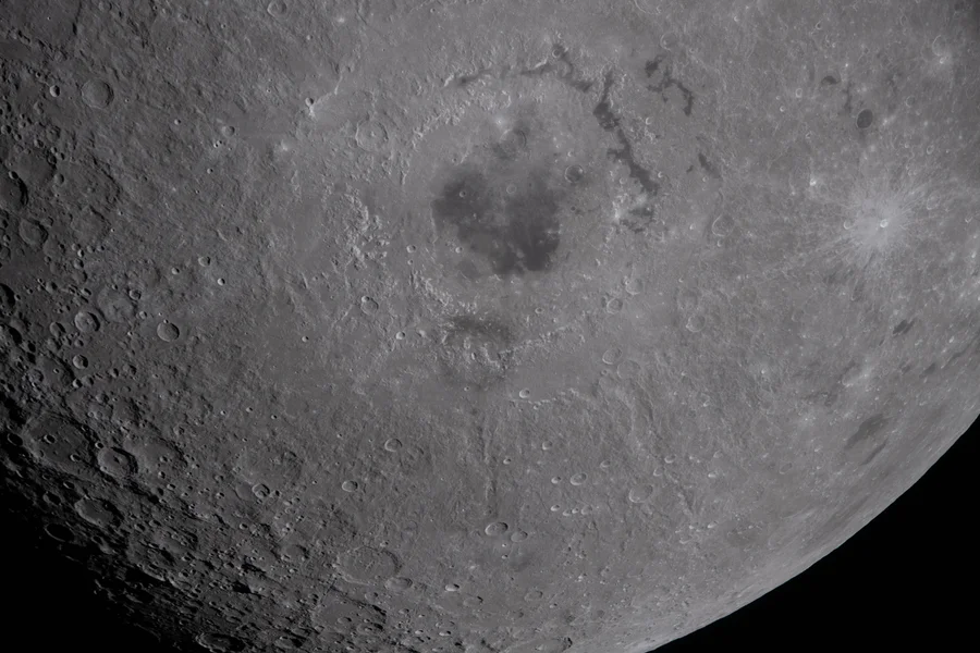 A close-up photo of the moon with a large basin visible in the center.