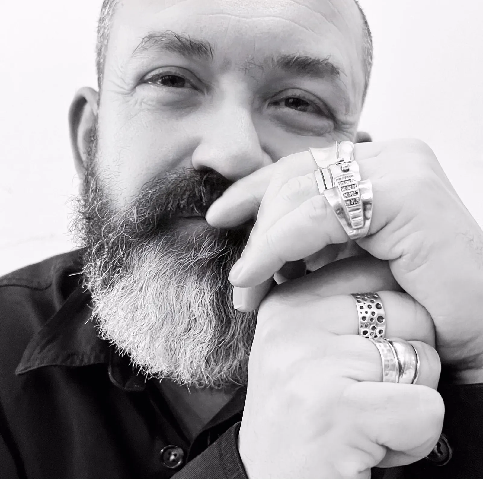 Image may contain Head Person Face Beard Accessories Jewelry Ring Adult Body Part Finger Hand and Photography