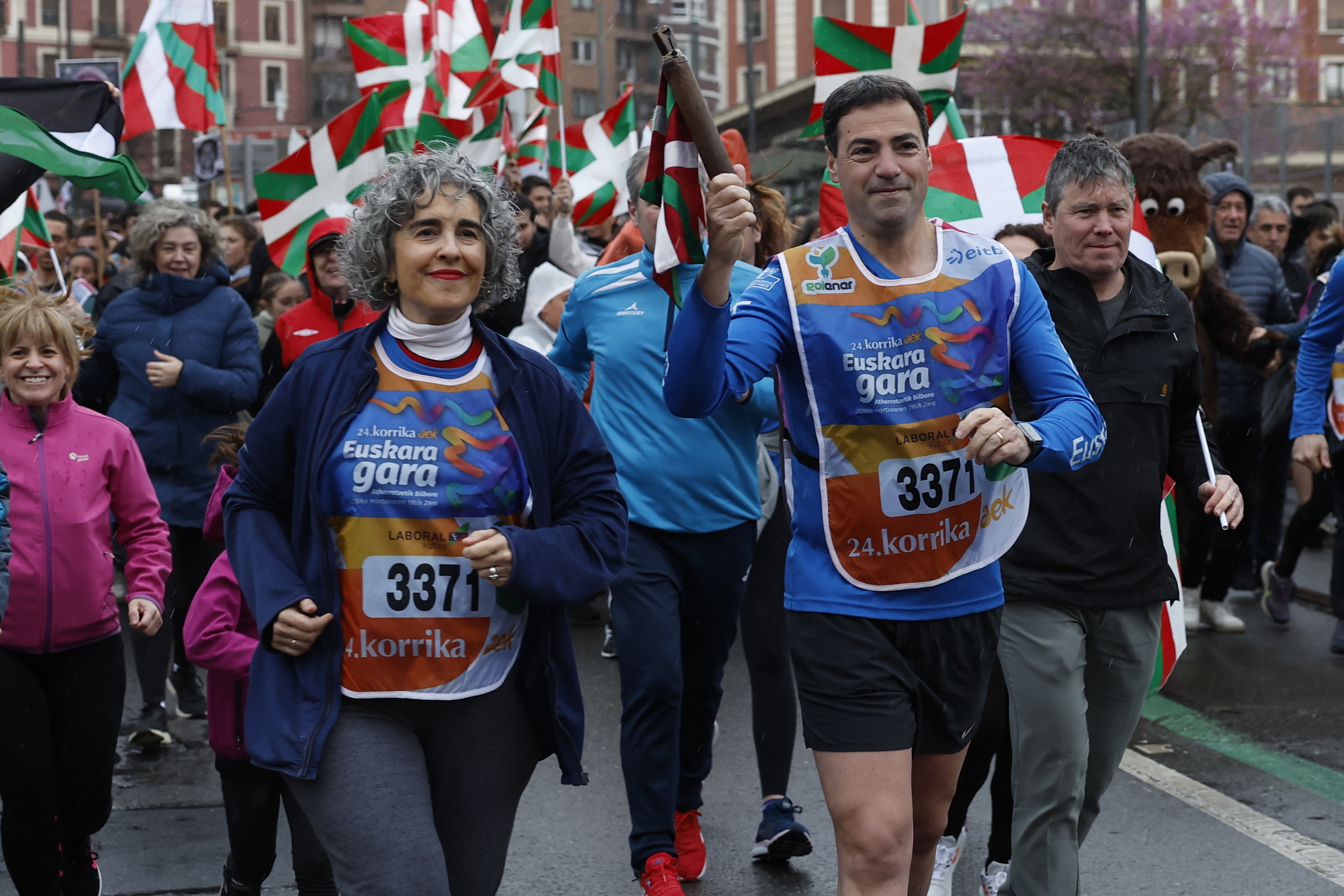 El lehendakari Imanol Pradales porta el testigo de la Korrika junto a la consejera de Euskadi Ibone Bengoetxea en el final de la carrera en Bilbao.