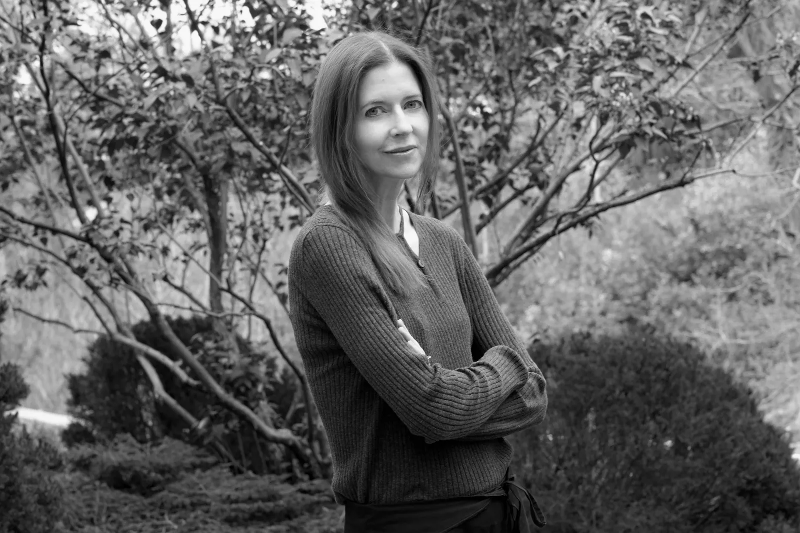 Image may contain Clothing Knitwear Sweater Face Head Person Photography Portrait Adult Happy Smile and Plant