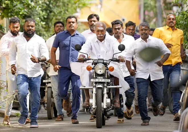 Puducherry Chief Minister N Rangasamy arrives on a motorcycle to cast his vote at a polling station in the Union Territory