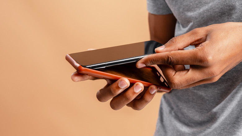 Person placing phone inside of a case against an orange background