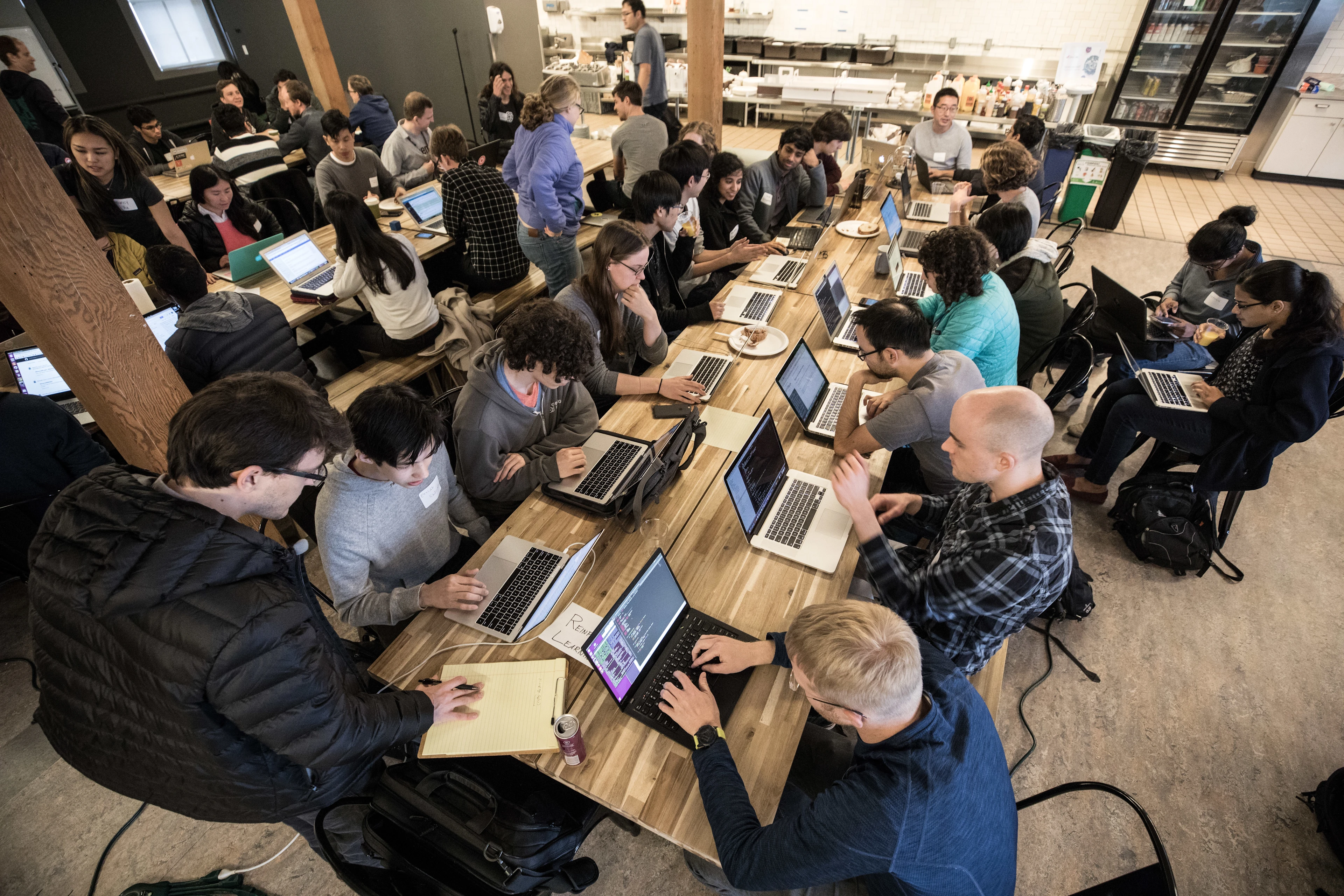 Aerial shot of a group of people sitting around a large table, working on their laptops