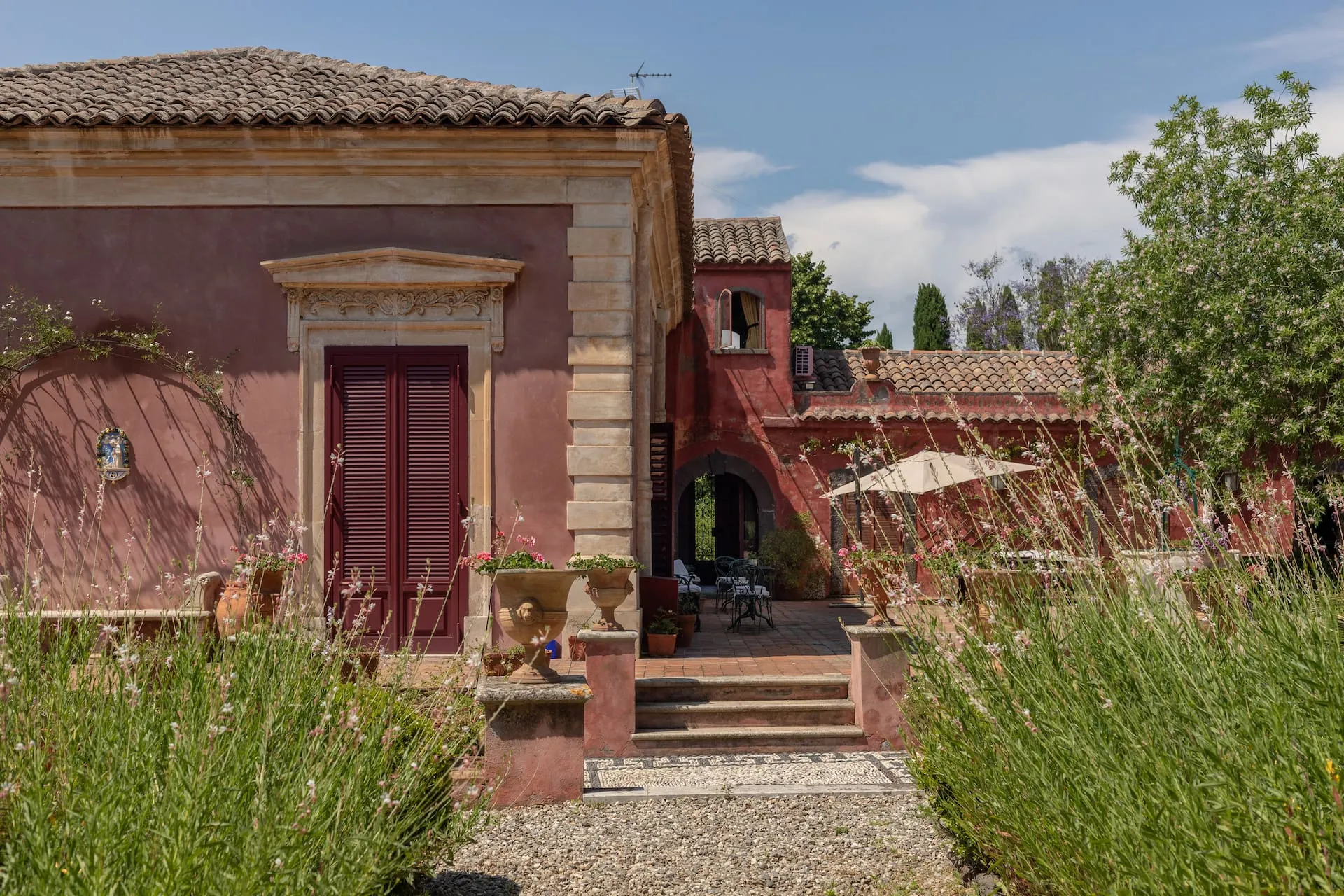 Image may contain Architecture Building House Housing Villa Hacienda Plant Potted Plant Road Person City and Door