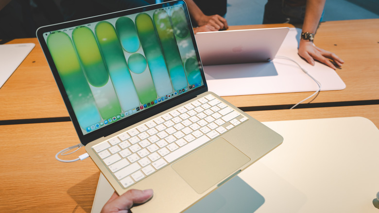 The MacBook Neo in hand in a store.