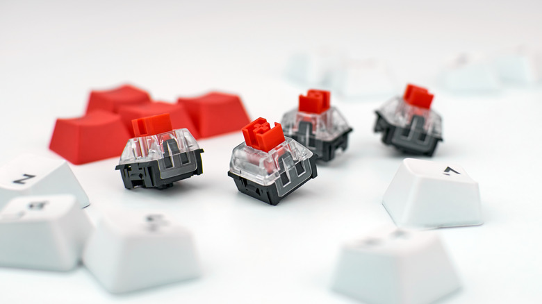 keyboard switches on a white table next to white keycaps