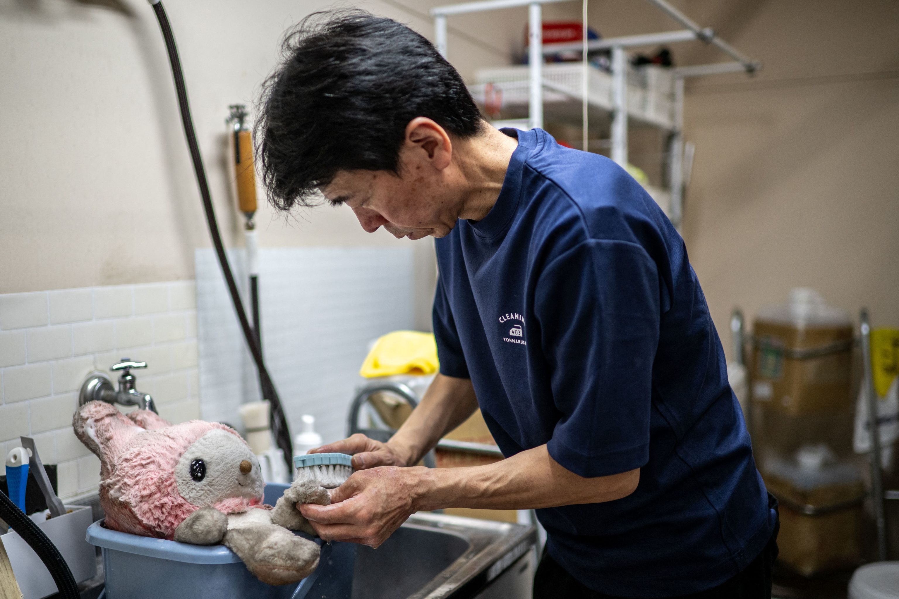 Un empleado de Cleaning Yonmarusan aseando a unos peluches.