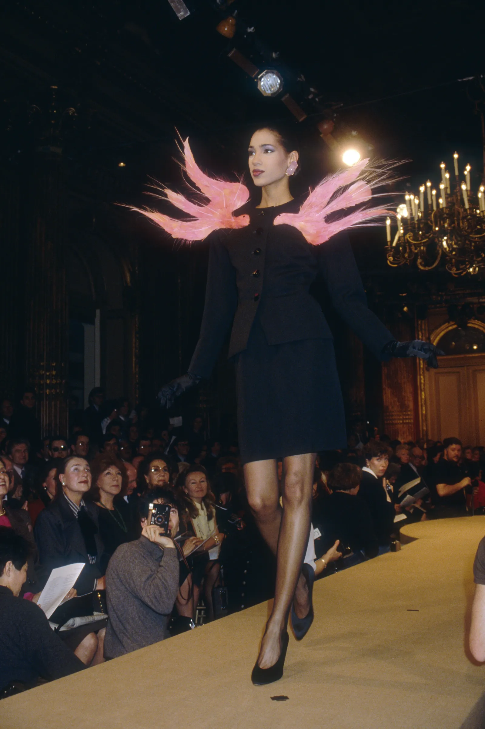 A fashion model wears a haute couture suit with pink accents by French fashion designer Yves Saint Laurent. She is...