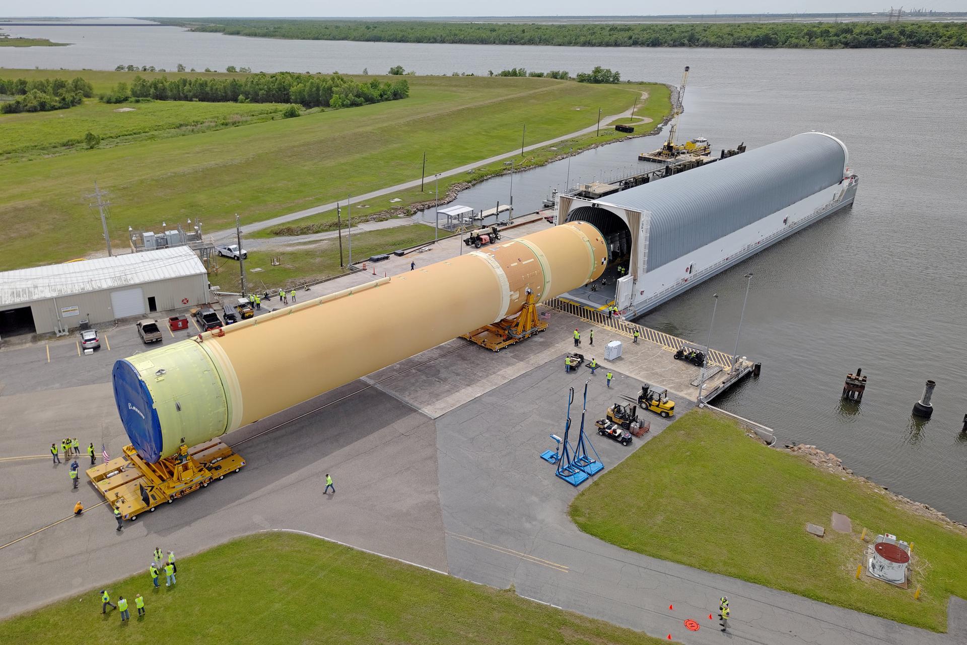 NASA moved the core stage, or the largest section, of the SLS (Space Launch System) rocket that will launch the crewed Artemis III mission in 2027 from the agency’s Michoud Assembly Facility to the agency’s Pegasus barge in New Orleans on April 20. The barge will ferry the top four-fifths – the section containing the liquid hydrogen tank, liquid oxygen tank, intertank, and forward skirt – of the SLS core stage to NASA’s Kennedy Space Center in Florida to complete outfitting and vertical integration.  Teams with NASA and Boeing, the SLS core stage lead contractor, used specialized transporters to guide the top four-fifths from the NASA rocket factory to Pegasus. Prior to the move, technicians added an engine section transportation simulator to the rocket stage for shipment to the Space Coast.  Next year’s Artemis III mission will launch astronauts to Earth’s orbit aboard the Orion spacecraft on top of SLS to test rendezvous and docking capabilities between Orion and commercial spacecraft needed to land Artemis IV astronauts on the Moon in 2028. NASA’s SLS is the only rocket capable of sending Orion, astronauts, and supplies to the Moon in a single launch. 