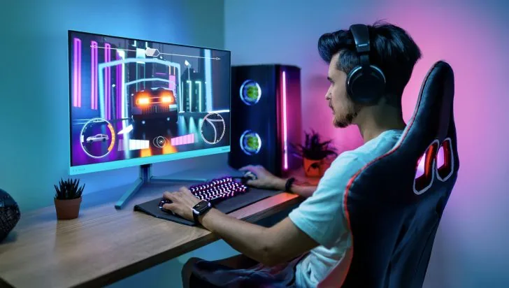 飞利浦发布 27M2N5201P 游戏显示器:原生 240Hz 高刷、1ms 响应 A person is playing a racing game on a Philips Evnia monitor at a gaming setup with a custom-built PC and RGB lighting.