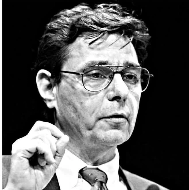 Black and white portrait of Murray Stahl, a man with glasses, looking thoughtful, with his hand raised near his face.