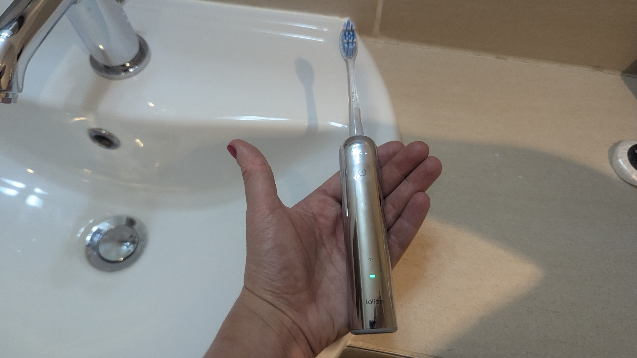 Laifen Wave Pro toothbrush during review in the hand of the reviewer. The battery indicator is lit up green.
