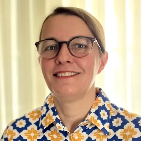 A woman wearing glasses …colourful floral shirt.