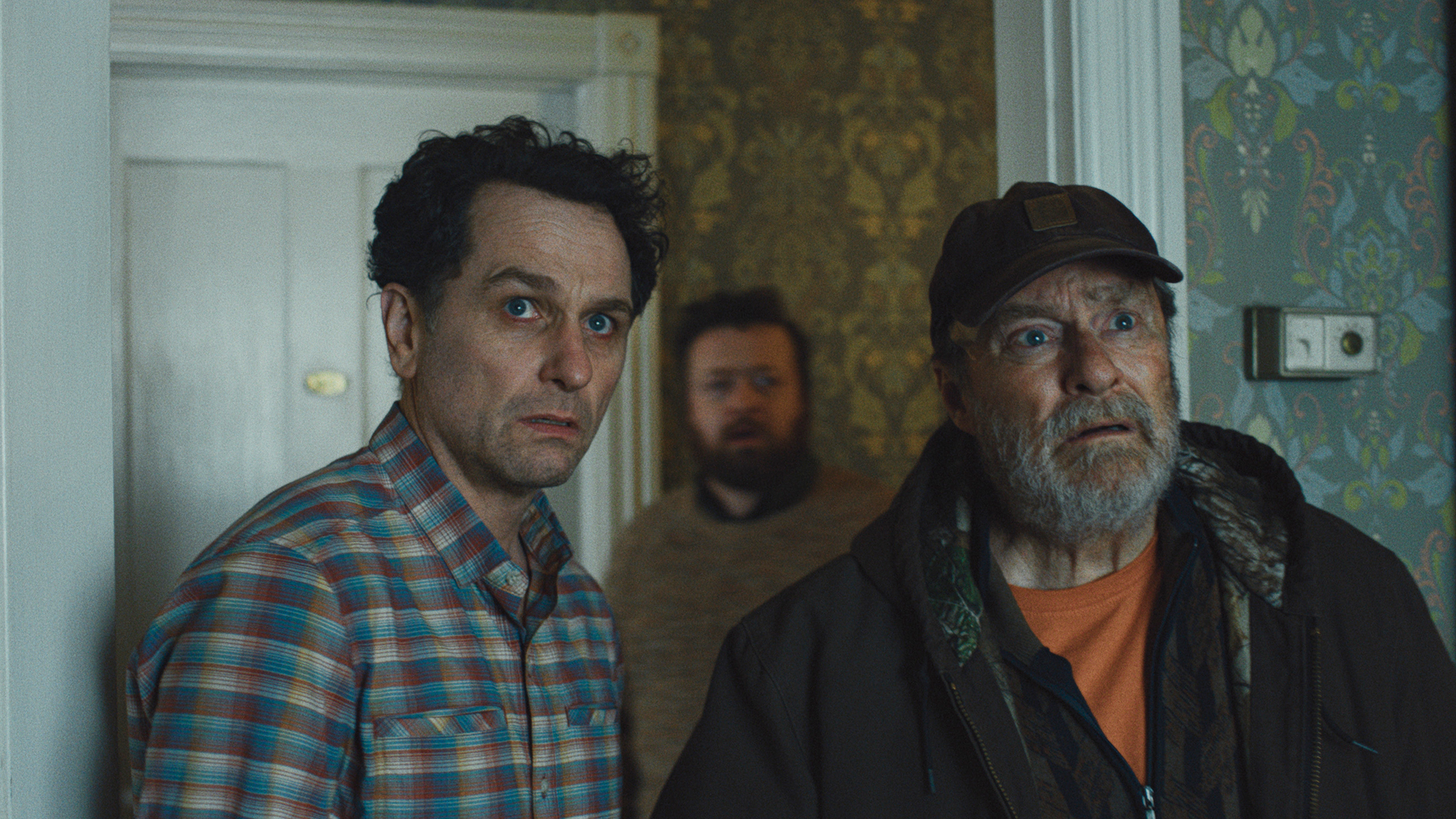 Tom, Wyck, and another man looking worried as they view a hotel room in Widow's Bay