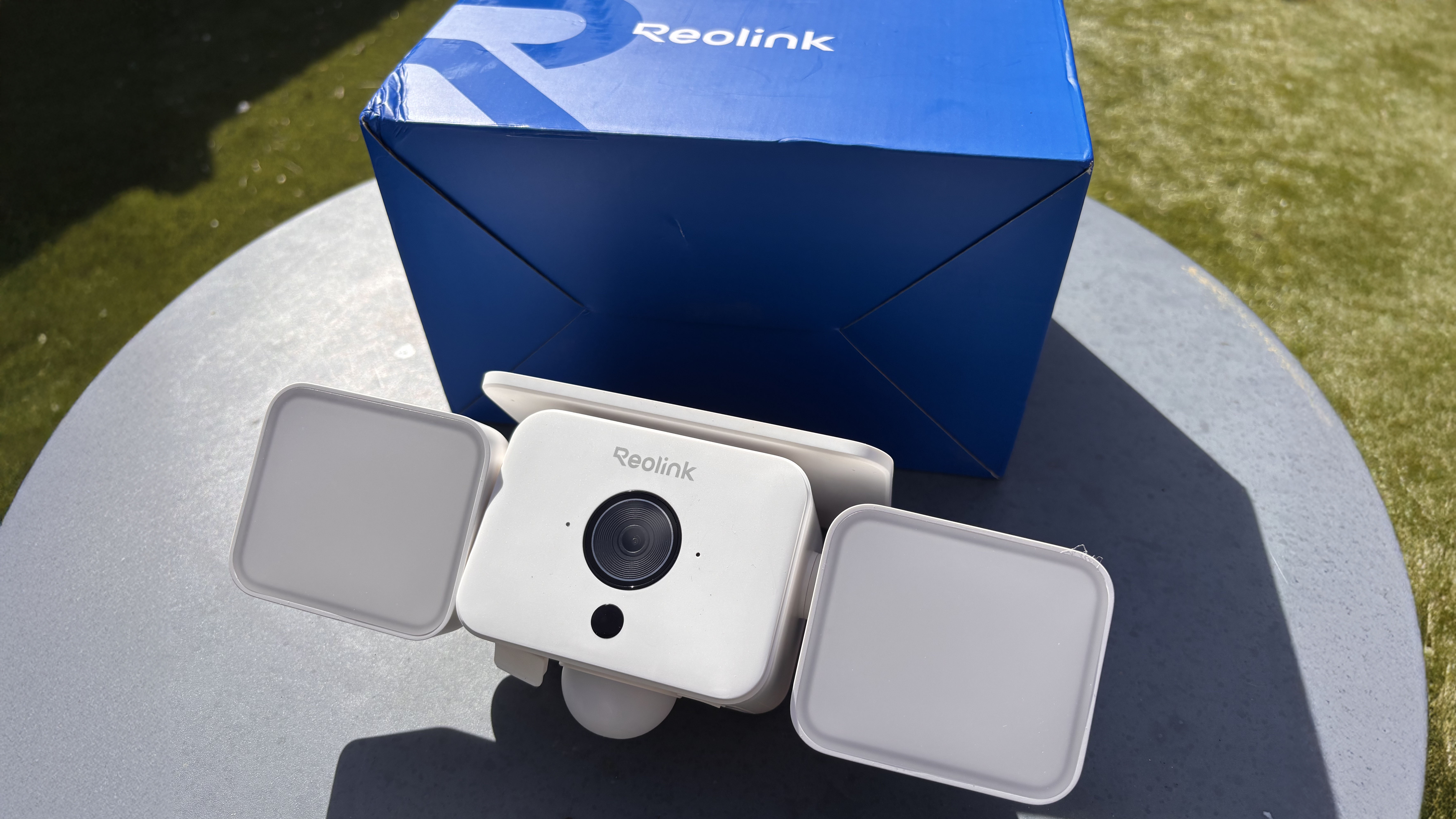 Reolink Solar Floodlight Cam with packaging on outdoor table
