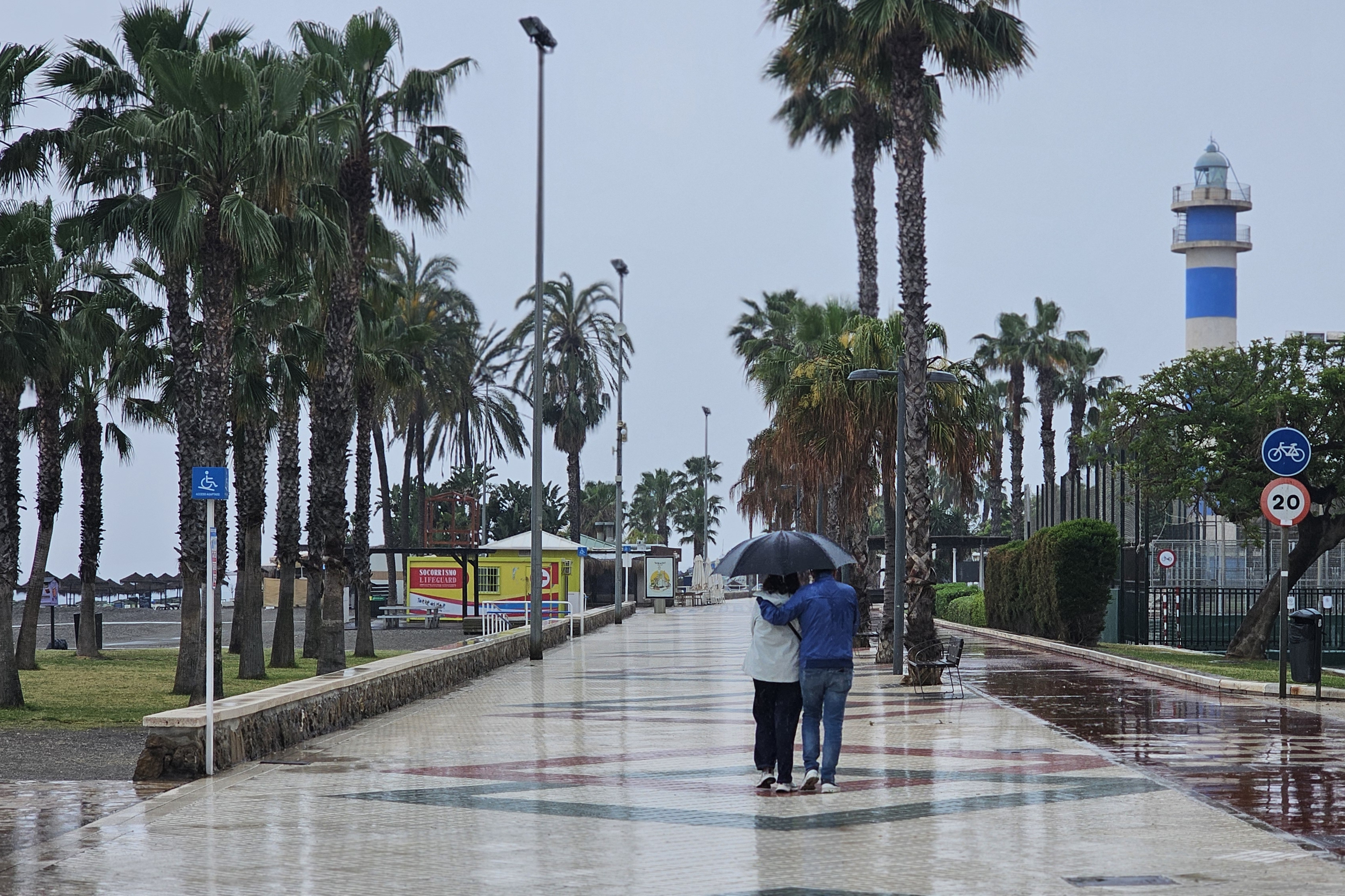 Una pareja pasea bajo la lluvia en un paseo mar�timo.