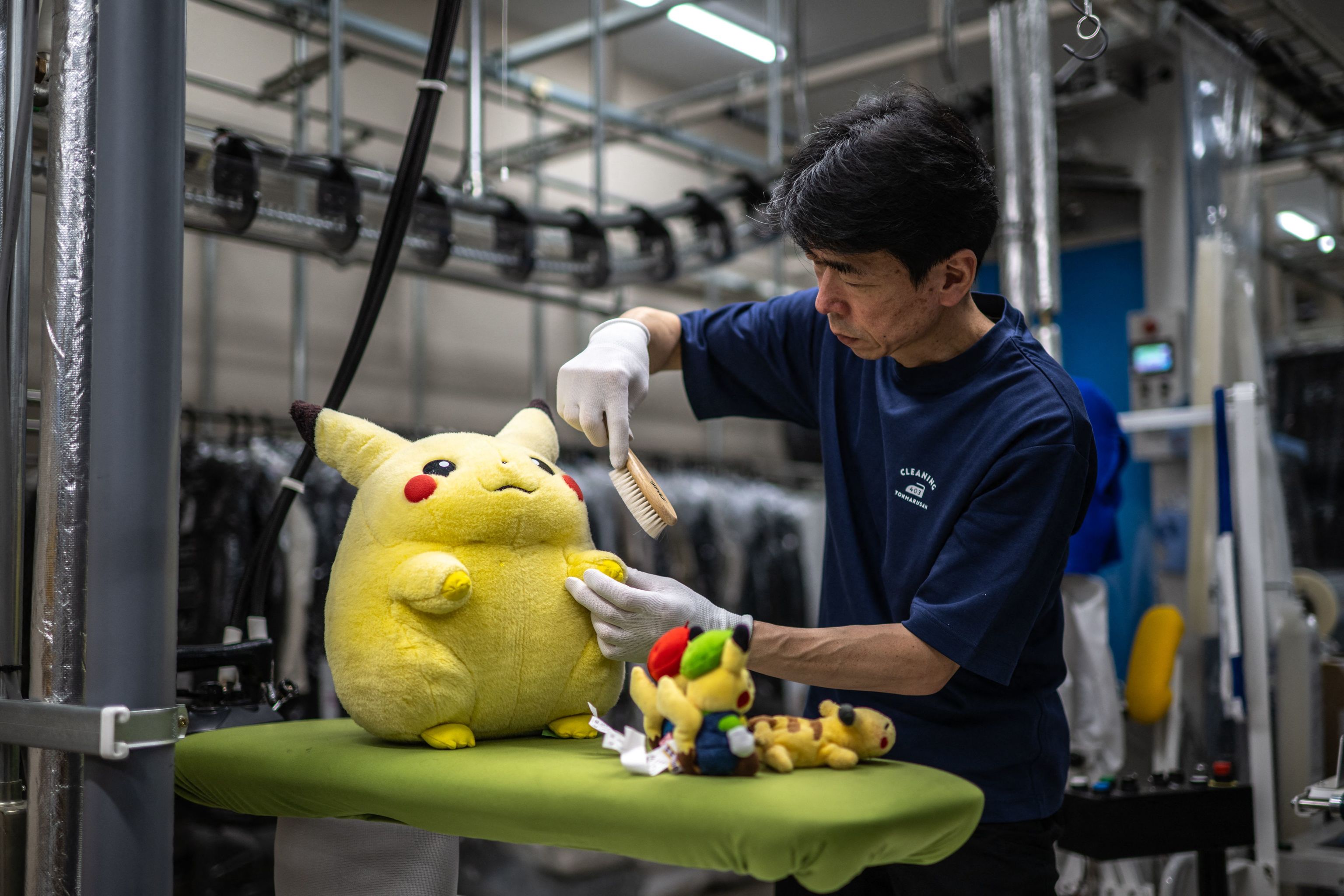 Un empleado de Cleaning Yonmarusan aseando a unos peluches.