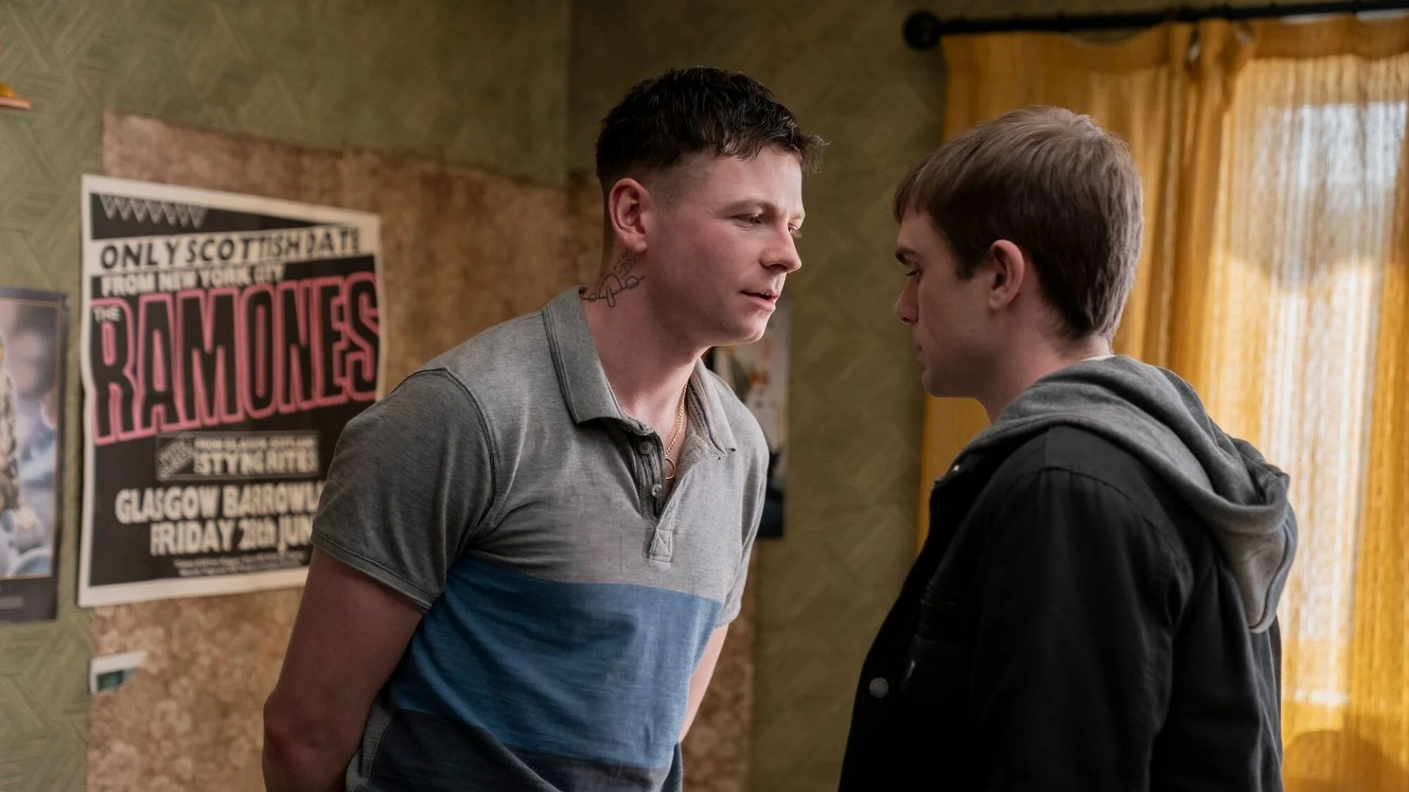 Two teenagers stand facing each other in a bedroom.