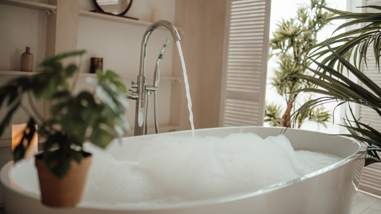 bathtub with water flowing and bubbles on surface