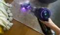Hand vacuuming rug with Shark cordless vacuum with coffee table and blanket in peripherals