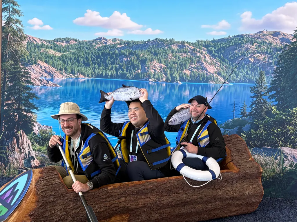 Attendees pose inside a wooden canoe at a photo op.