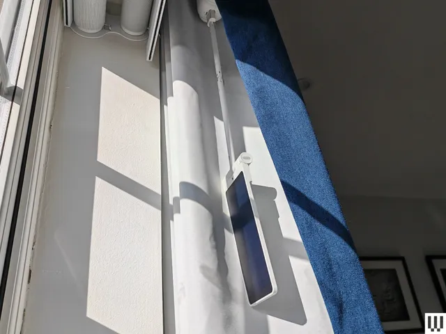 A narrow panel dangling from a curtain rod in a window ledge with a blue curtain surrounding it