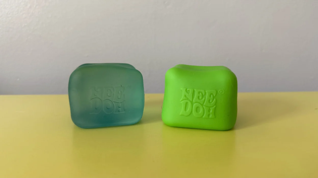Two NeeDoh Nice Cubes on a table