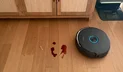 Narwal Flow 2 robot vacuum mopping up wine spill in front of credenza and dock