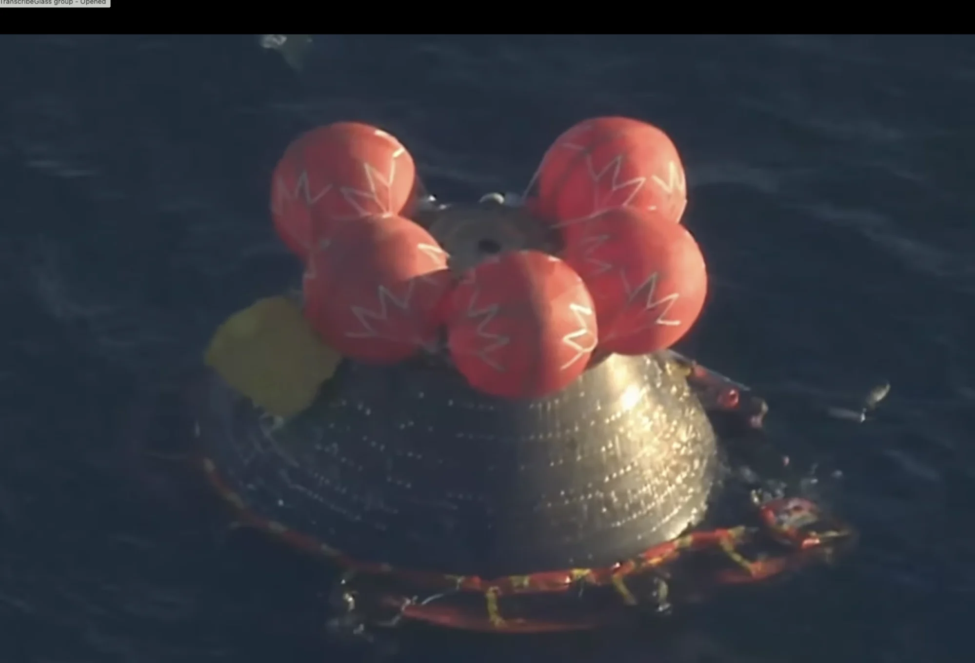 The Orion crew capsule floating in the pacific with red balloons atop