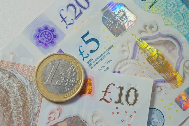 One euro coin resting on british pound banknotes symbolizing currency exchange