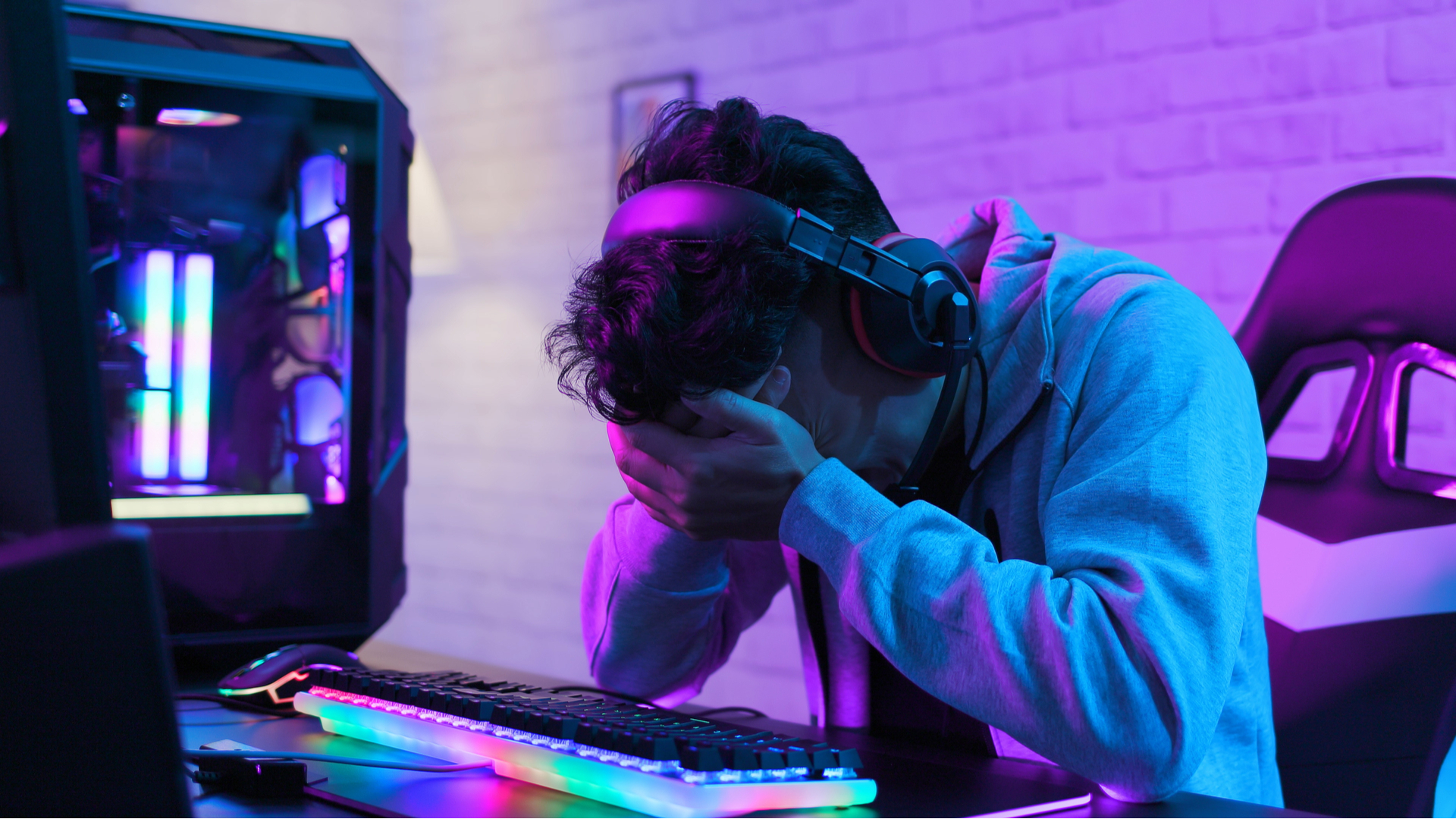 Sad gamer sat at their PC, head in hands, worrying about high component prices