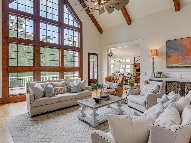 A living room with high, beamed ceilings and a wall completely covered in windows.