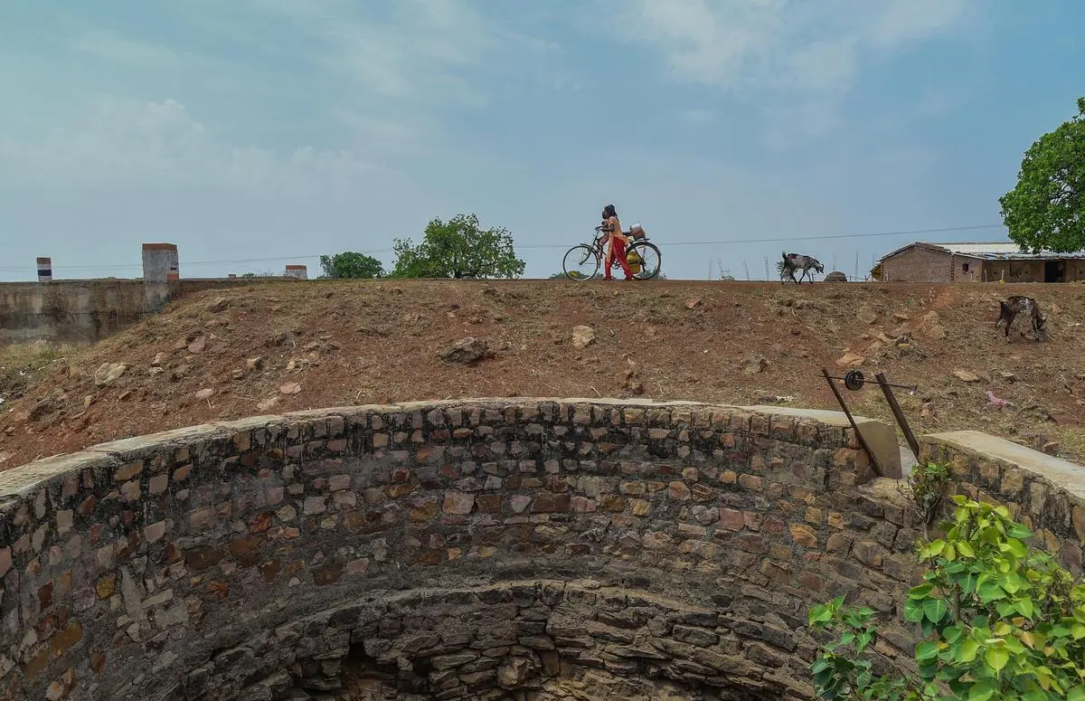 A girl carrying water buckets crosses a dried well on May 21, 2025, in Mauganj, Madhya Pradesh, India. Large parts of North India, including regions in Uttar Pradesh, Haryana, Punjab, and parts of Bihar depend largely on groundwater.