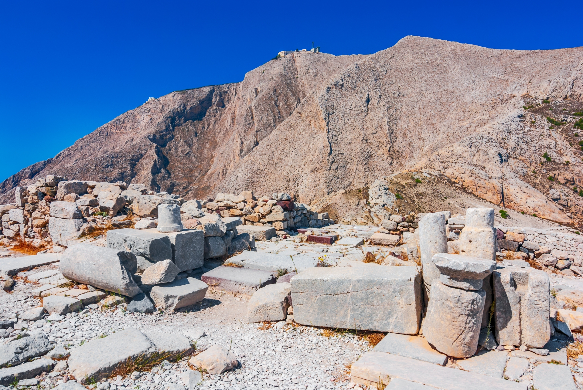 A series of white stone blocks make an archaeological site with tall mountains in the background