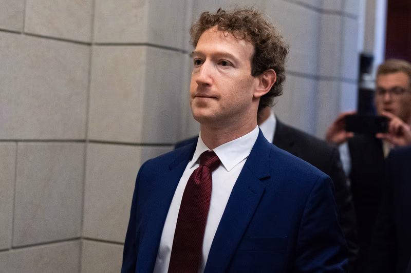 Mark Zuckerberg wears a navy suit and burgundy tie walking at the US Capitol.