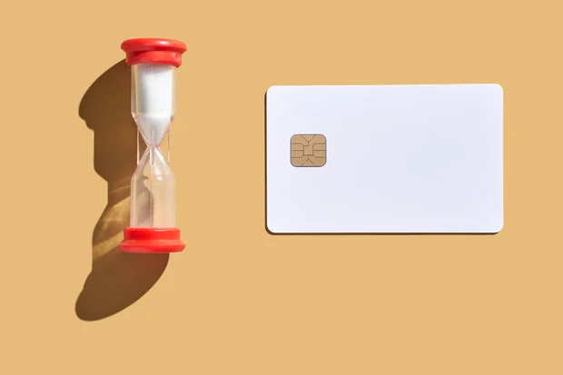 Time management concept with hourglass and blank credit card on beige 