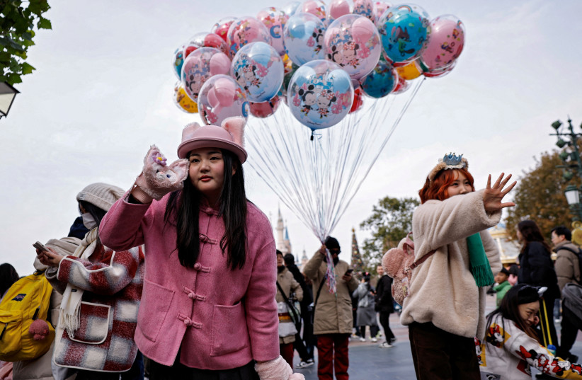 A VISITOR wearing a hat and a pair of gloves with LinaBell design poses for pictures at Shanghai Disneyland, in Shanghai, China December 23, 2024.