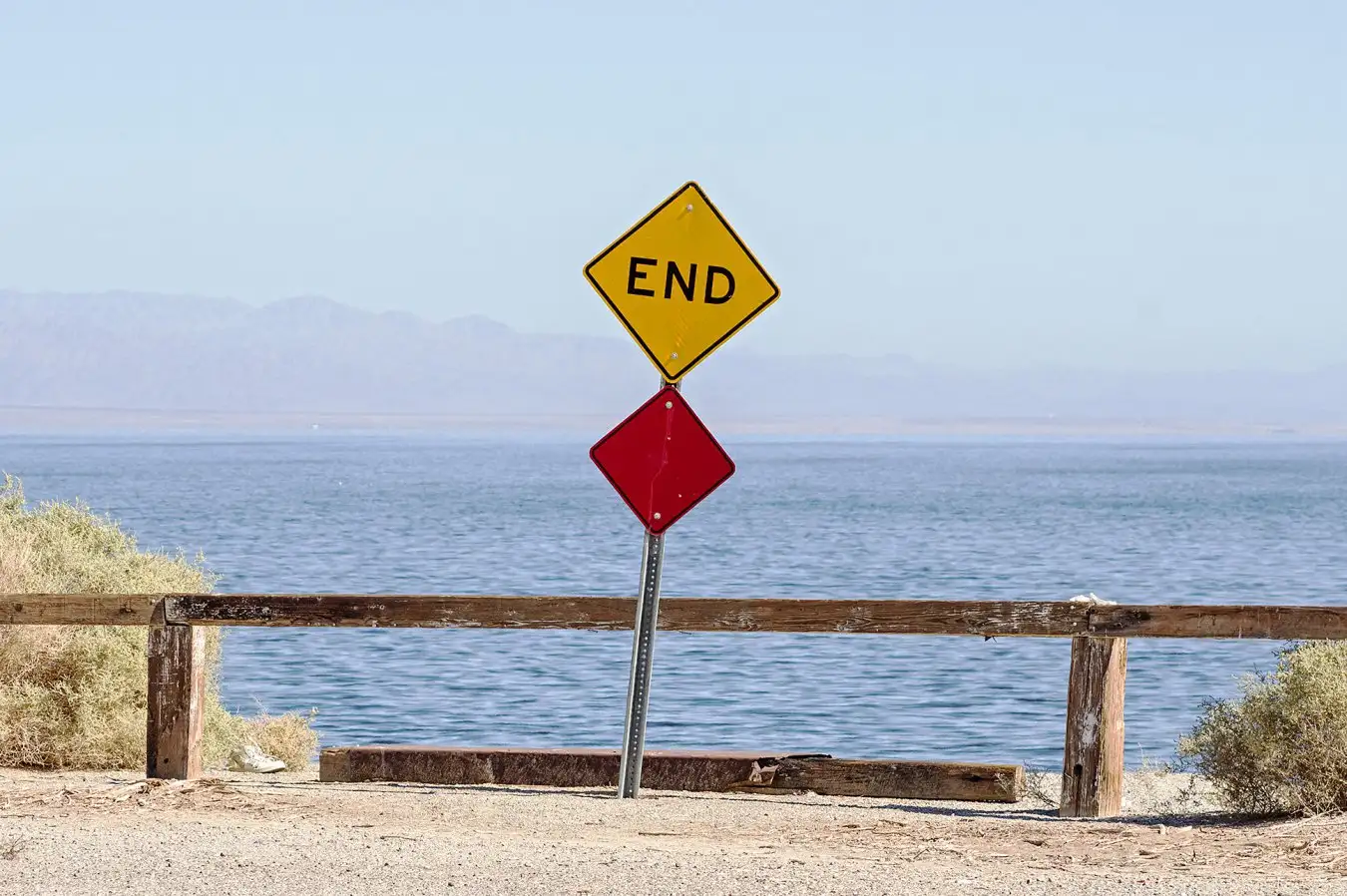 EAF952 the end of the road where a road dead ends into the Salton Sea with a sign and barrier