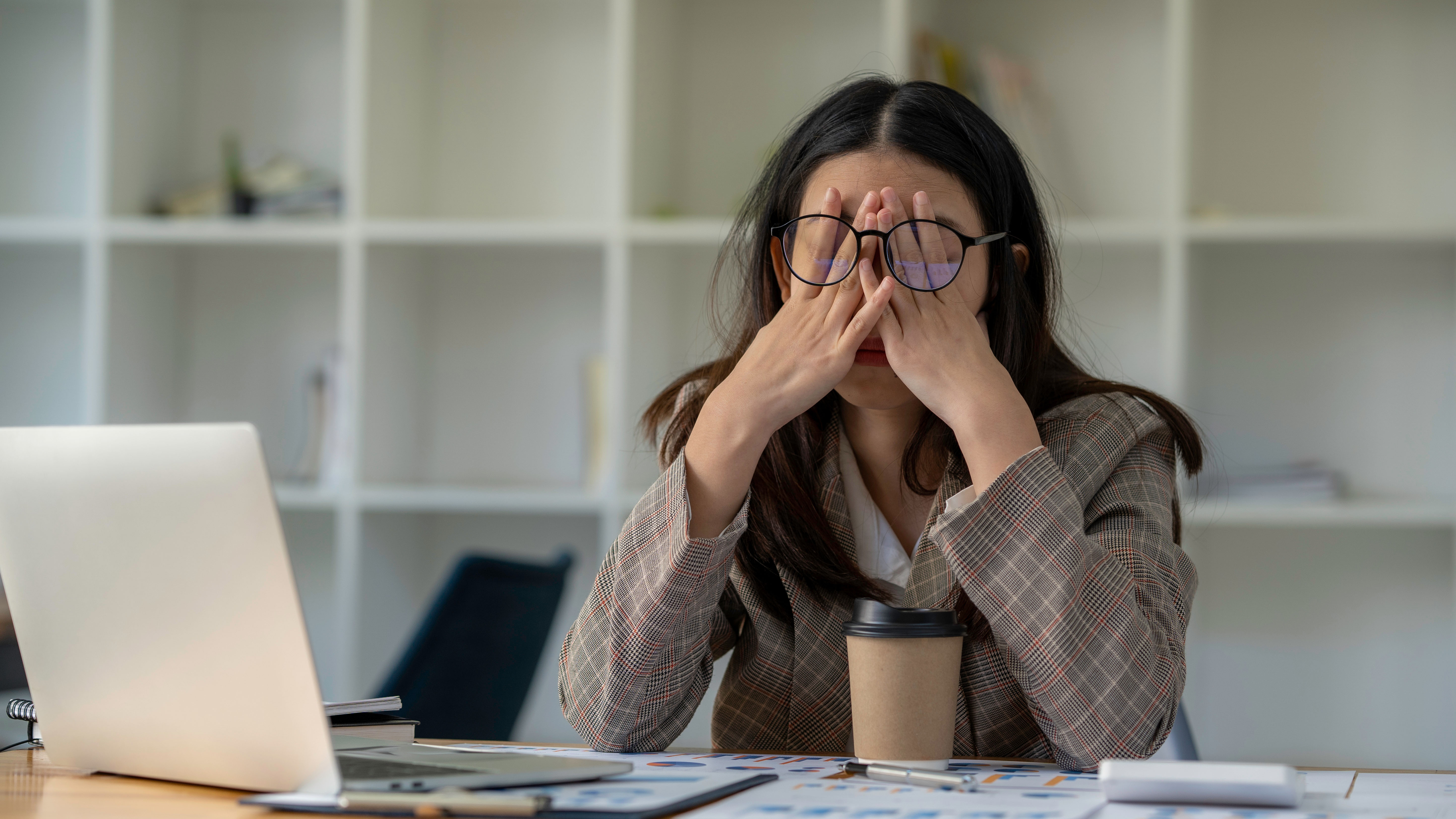 Woman looking tired in front of her Windows 11 laptop, rubbing her eyes